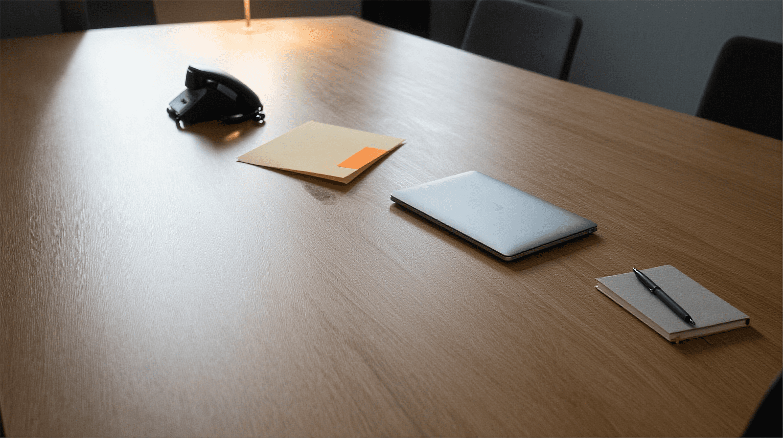 Bovenaanzicht van een conferentietafel met vier geïsoleerde werkplekken; één werkplek heeft een oranje accent, de andere drie blijven gescheiden — symbool voor agents van verschillende leveranciers die niet samenwerken.